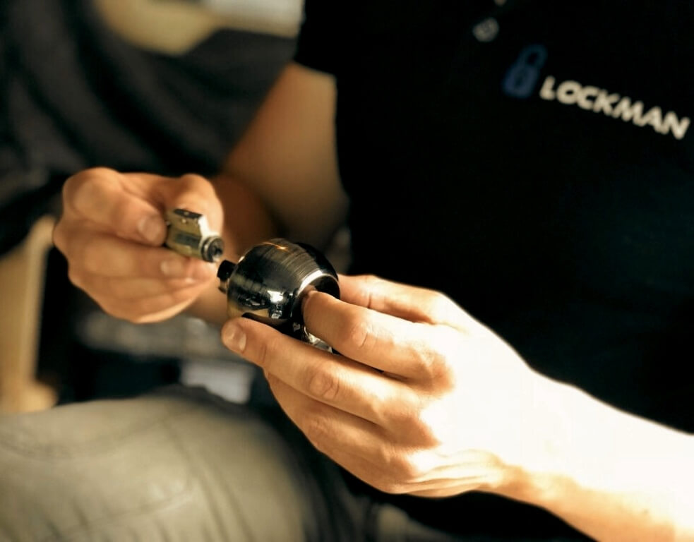 Hands dismantling a lock cylinder over a work surface