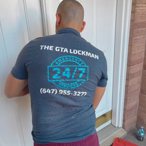 Locksmith wearing a shirt with “THE GTA LOCKMAN,” “EMERGENCY 24/7,” and phone number (647) 955-3277