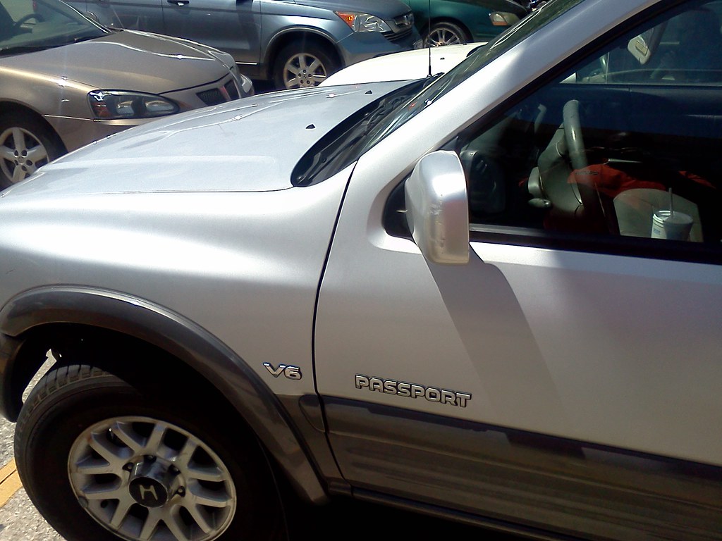 Silver SUV with V6 and Passport badges parked in a lot