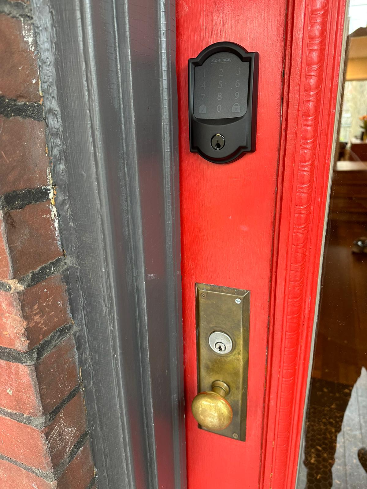 Electronic lock housing above brass hardware on a red entrance door
