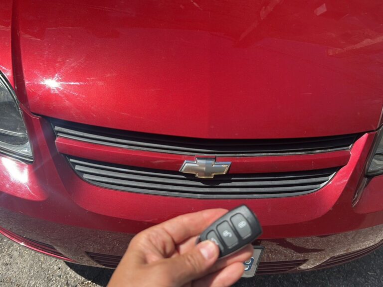 Car key fob held in front of a red car after programming