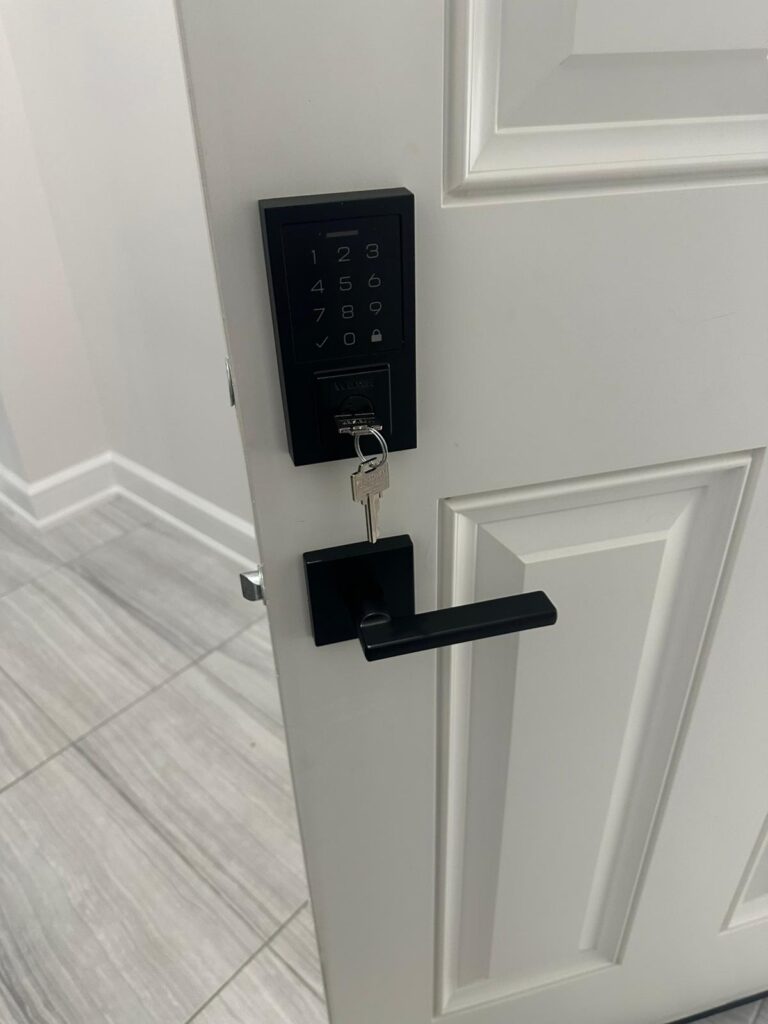 Black keypad deadbolt with matching lever on a white panelled door