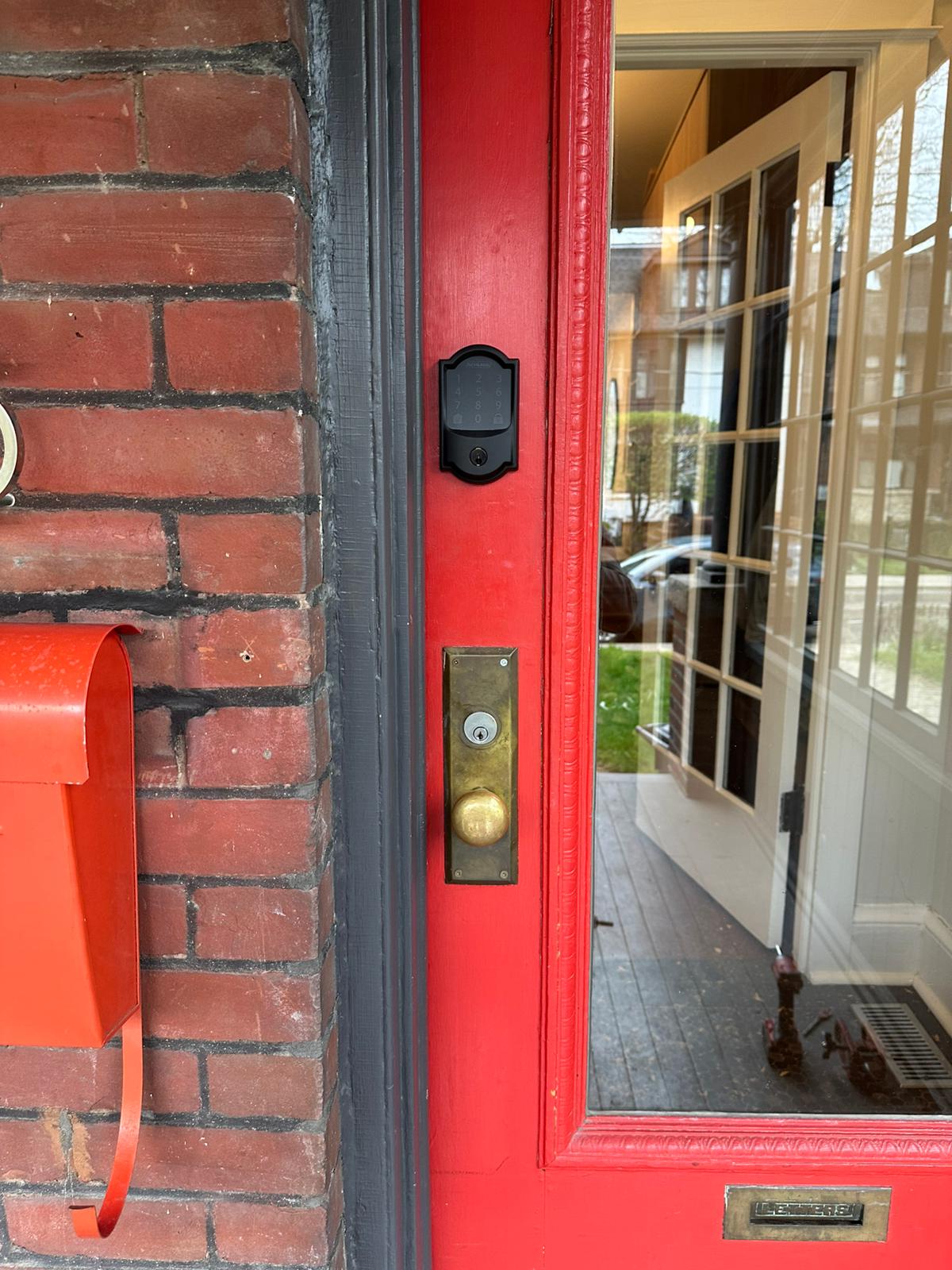 Red glass-panel front door with keypad deadbolt and brass knob