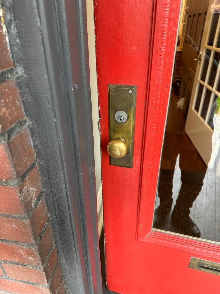 Brass deadbolt and lock hardware on a red front door
