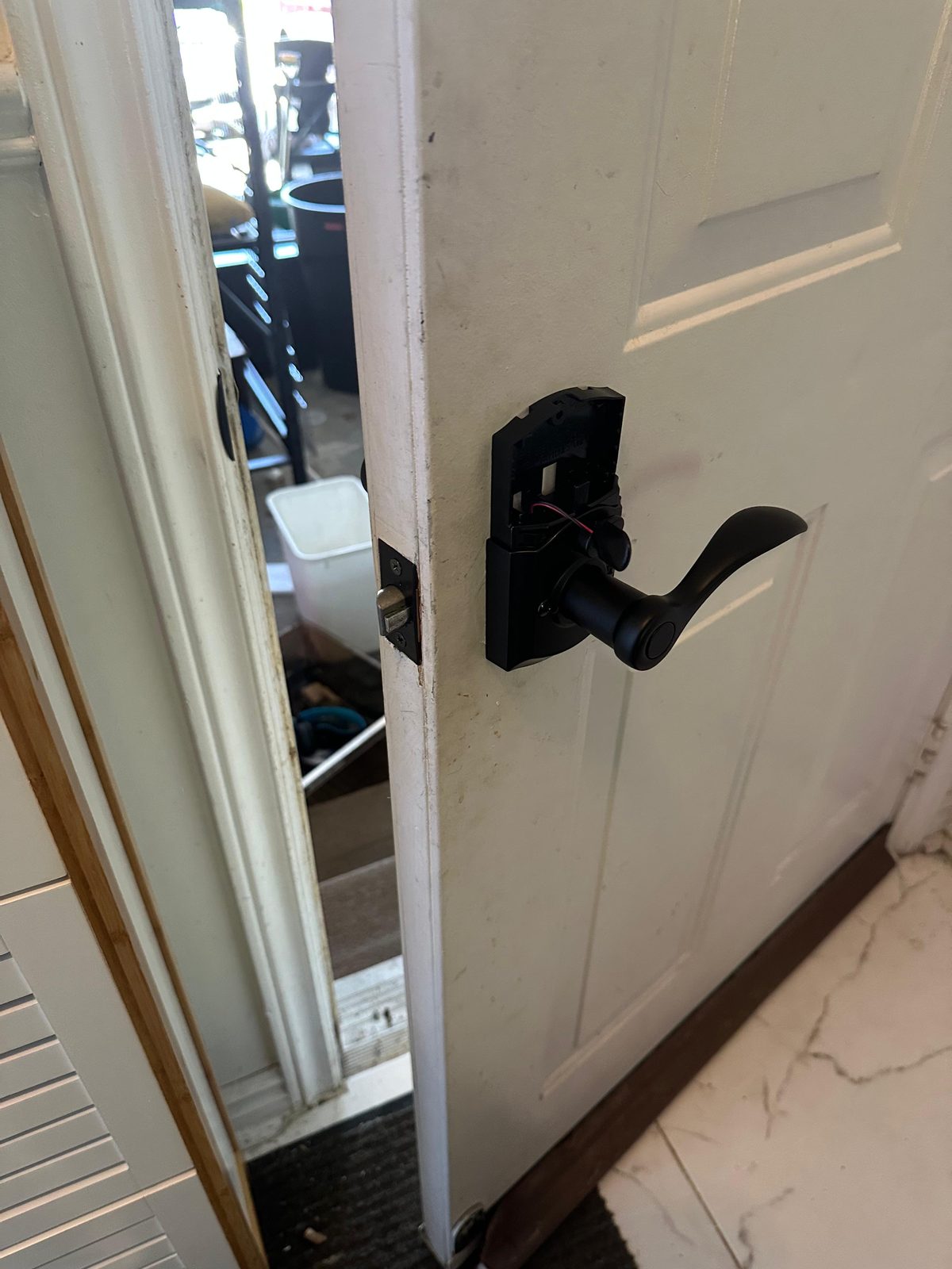Black lever handle on a white door opening into a garage