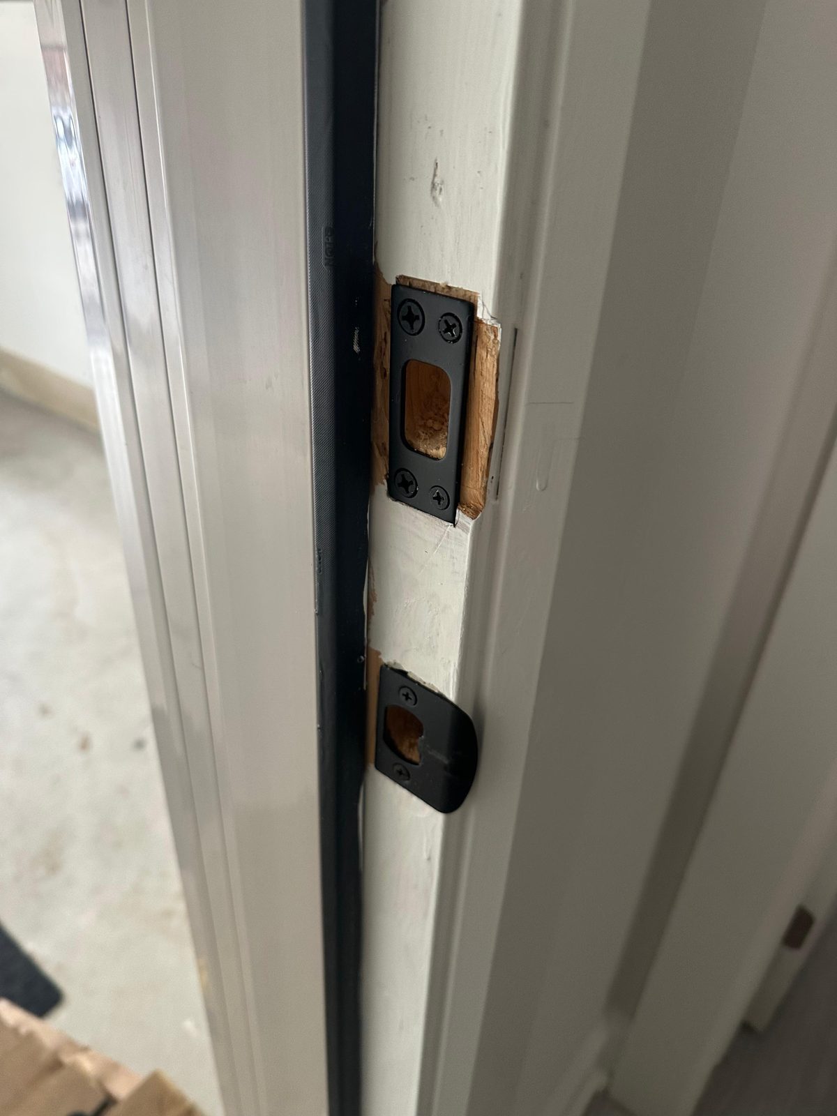 Latch and strike plates fitted on the edge of a white door frame