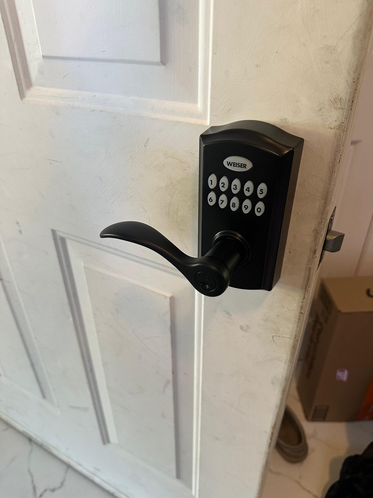Push-button keypad above a black lever lock on a white door