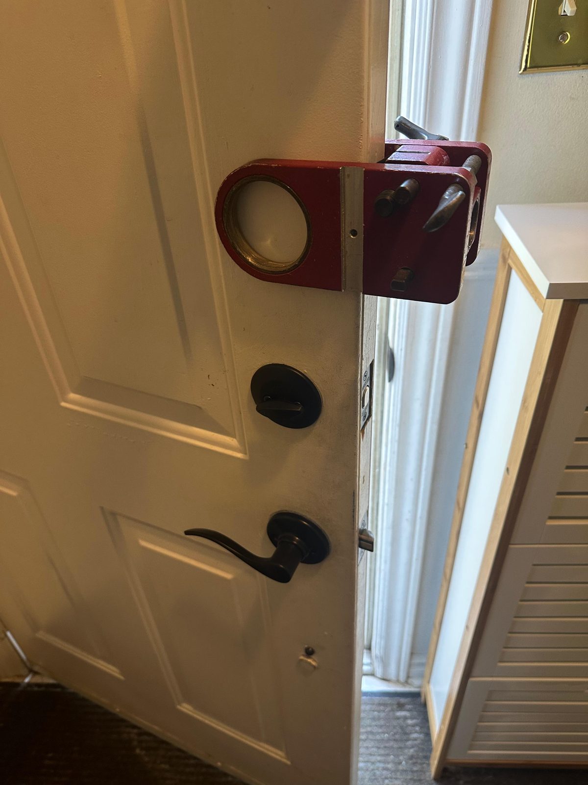 Red key lockbox hung on a door beside a black lever handle