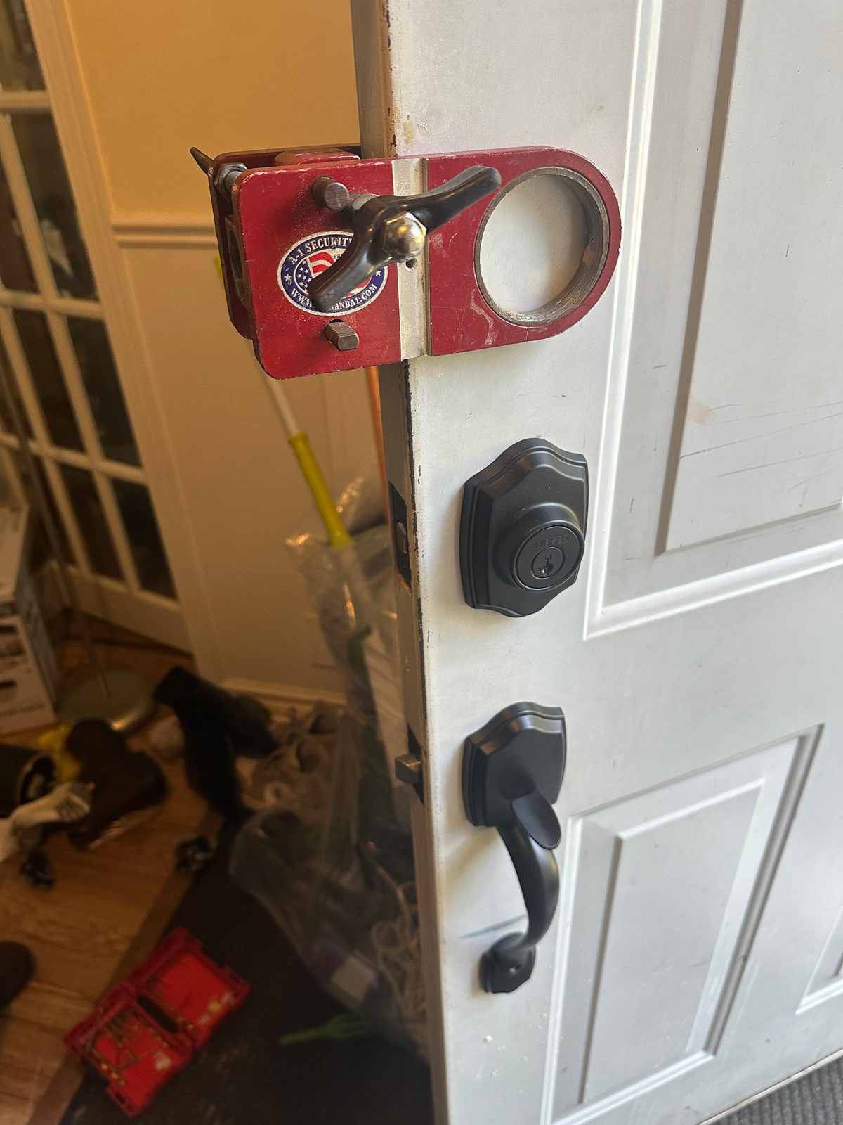 Red key lockbox hung on a glazed door beside a black deadbolt