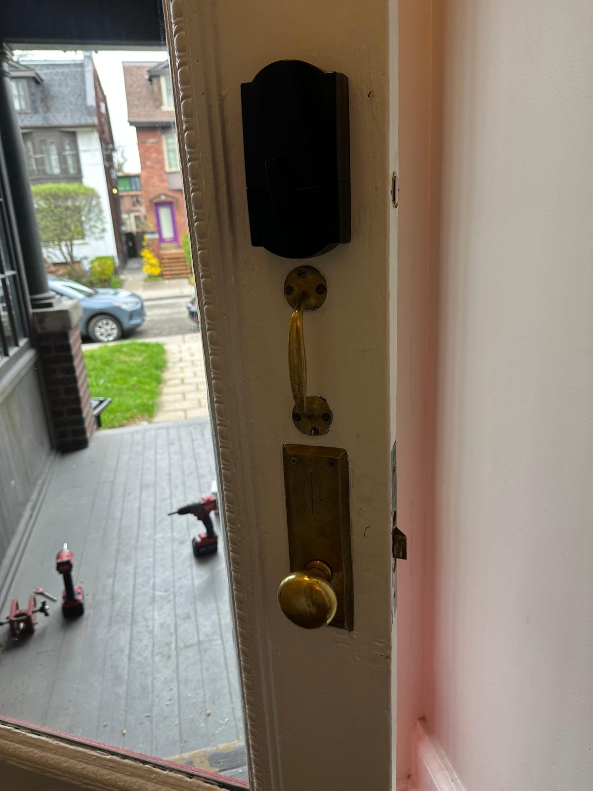 Black smart deadbolt fitted above a brass handleset on a white door