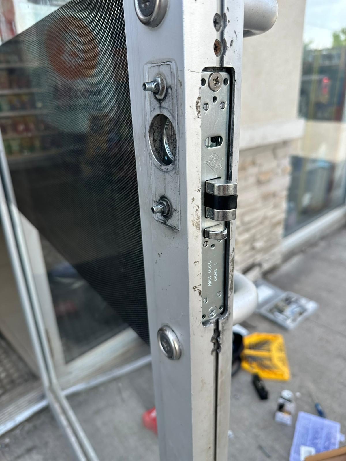 Storefront door hardware partly removed with tools on the mat below