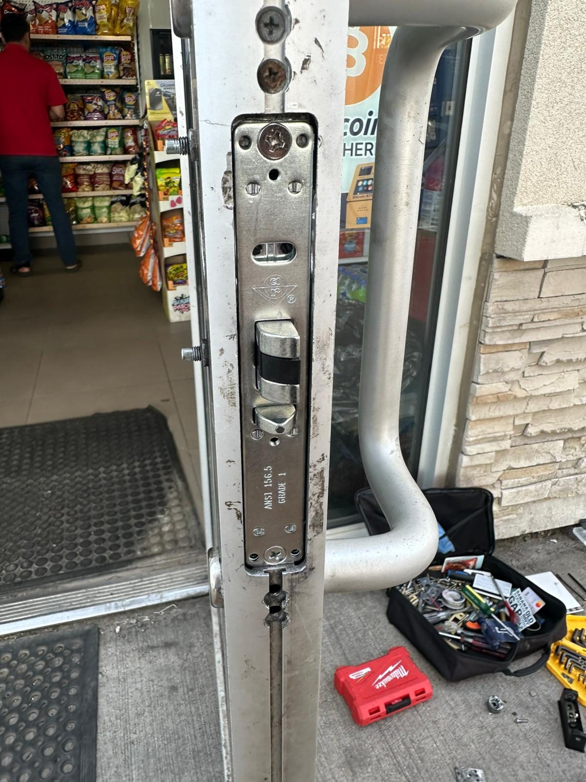 Latch strip along a storefront door edge with an open tool bag nearby