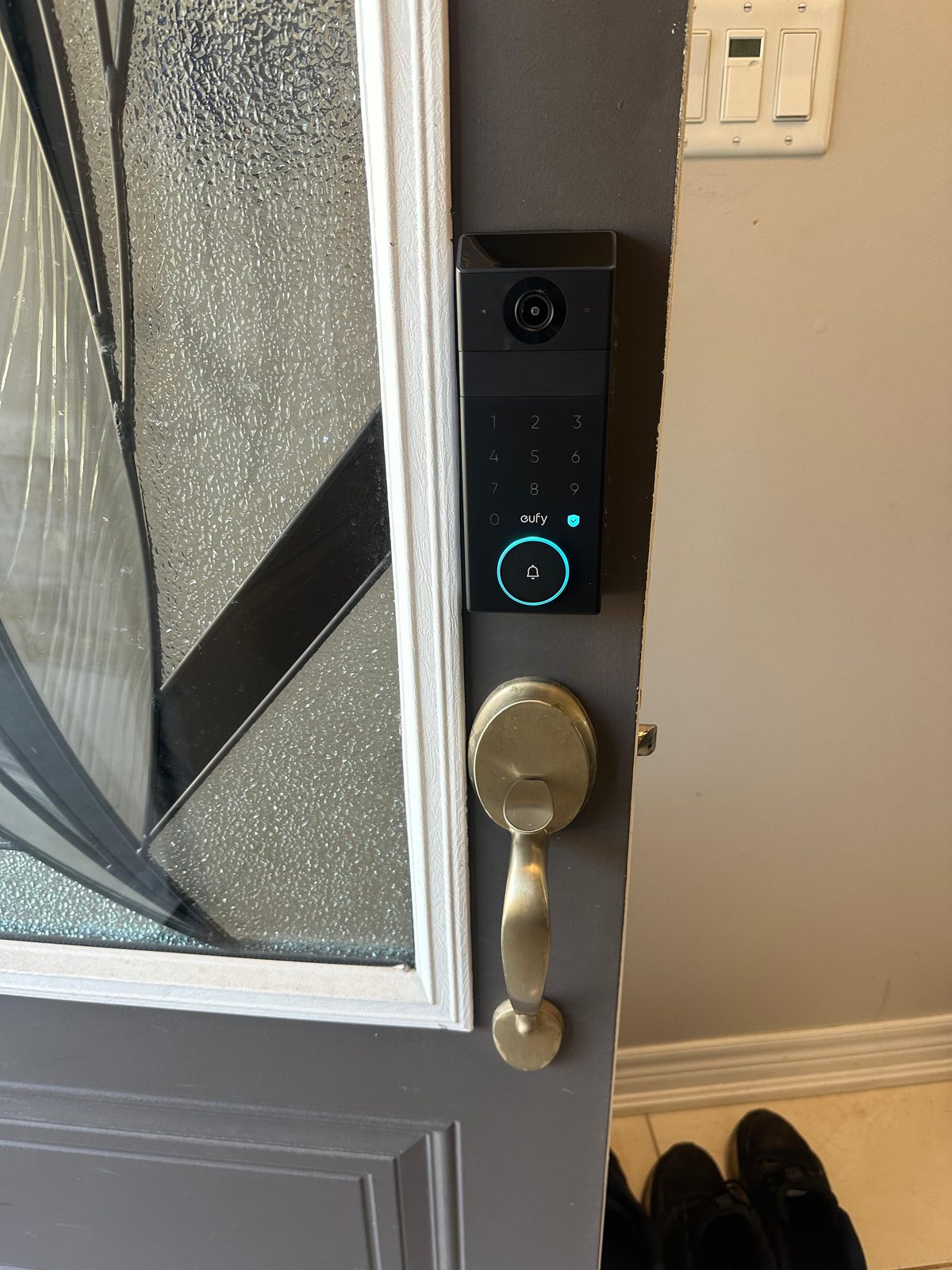 Video doorbell mounted beside a brass handleset on a white entrance