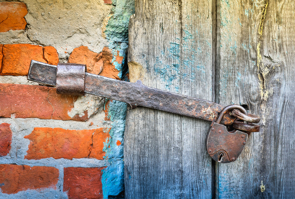 Rusty hasp and padlock on a weathered wooden door