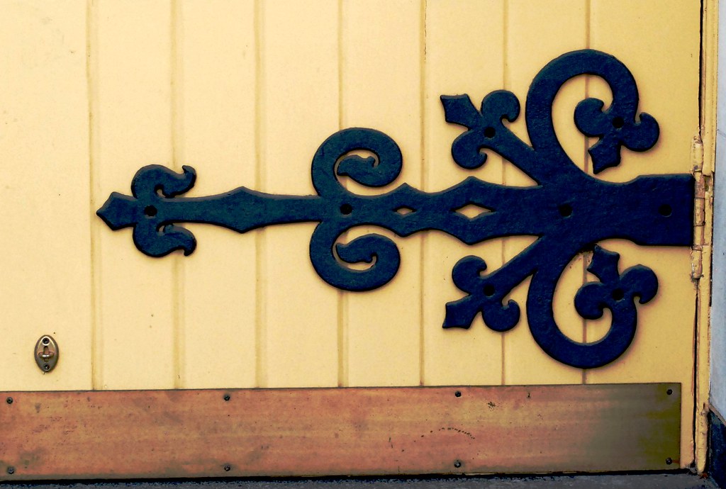 Decorative black strap hinge on a yellow wooden door