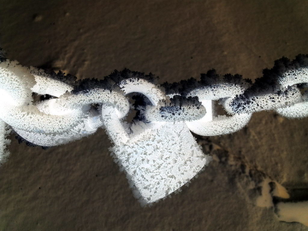 Frost-covered chain and padlock in winter